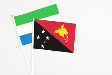 Papua New Guinea and Sierra Leone stick flags on white background. High quality fabric, miniature national flag. Peaceful global concept.White floor for copy space.