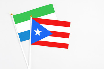 Puerto Rico and Sierra Leone stick flags on white background. High quality fabric, miniature national flag. Peaceful global concept.White floor for copy space.