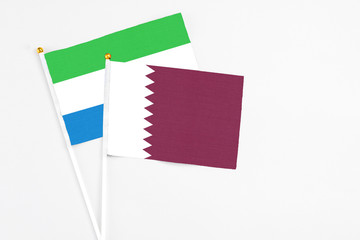 Qatar and Sierra Leone stick flags on white background. High quality fabric, miniature national flag. Peaceful global concept.White floor for copy space.