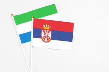 Serbia and Sierra Leone stick flags on white background. High quality fabric, miniature national flag. Peaceful global concept.White floor for copy space.