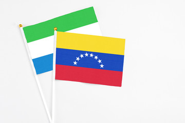 Venezuela and Sierra Leone stick flags on white background. High quality fabric, miniature national flag. Peaceful global concept.White floor for copy space.
