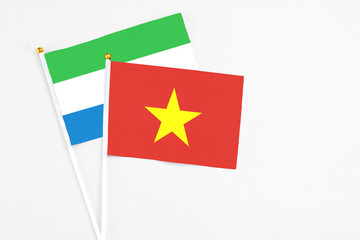 Vietnam and Sierra Leone stick flags on white background. High quality fabric, miniature national flag. Peaceful global concept.White floor for copy space.
