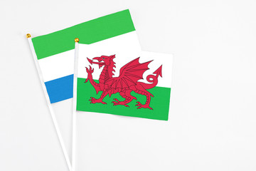 Wales and Sierra Leone stick flags on white background. High quality fabric, miniature national flag. Peaceful global concept.White floor for copy space.