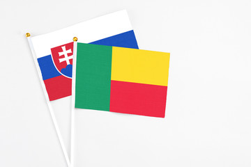 Benin and Slovakia stick flags on white background. High quality fabric, miniature national flag. Peaceful global concept.White floor for copy space.