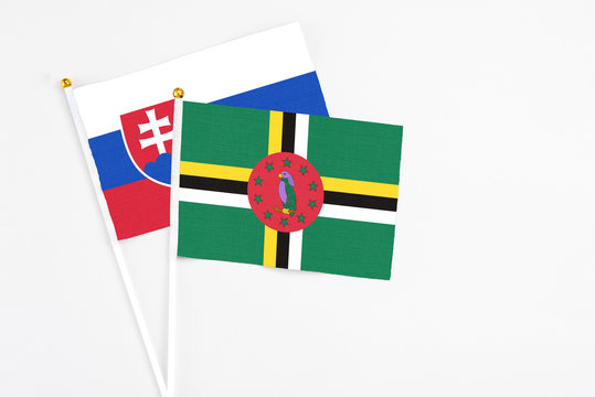 Dominica and Slovakia stick flags on white background. High quality fabric, miniature national flag. Peaceful global concept.White floor for copy space.
