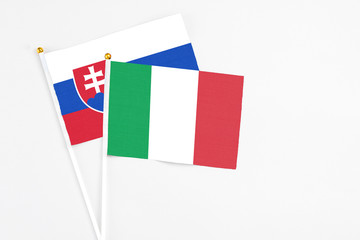 Italy and Slovakia stick flags on white background. High quality fabric, miniature national flag. Peaceful global concept.White floor for copy space.