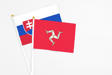 Isle Of Man and Slovakia stick flags on white background. High quality fabric, miniature national flag. Peaceful global concept.White floor for copy space.