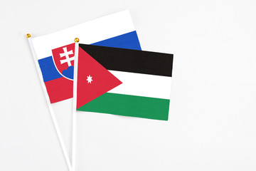 Jordan and Slovakia stick flags on white background. High quality fabric, miniature national flag. Peaceful global concept.White floor for copy space.