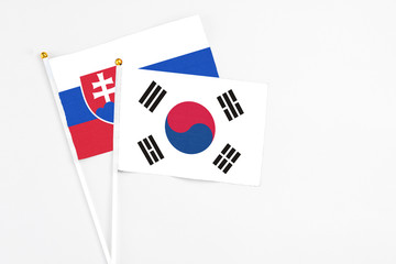 South Korea and Slovakia stick flags on white background. High quality fabric, miniature national flag. Peaceful global concept.White floor for copy space.