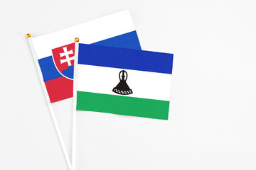 Lesotho and Slovakia stick flags on white background. High quality fabric, miniature national flag. Peaceful global concept.White floor for copy space.