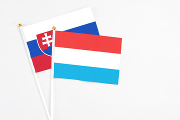 Luxembourg and Slovakia stick flags on white background. High quality fabric, miniature national flag. Peaceful global concept.White floor for copy space.