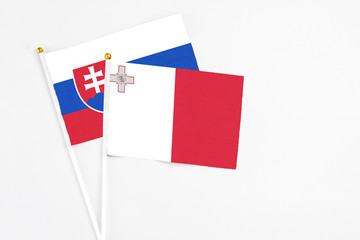 Malta and Slovakia stick flags on white background. High quality fabric, miniature national flag. Peaceful global concept.White floor for copy space.