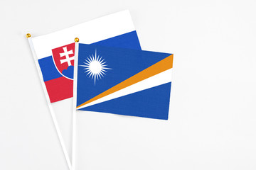 Marshall Islands and Slovakia stick flags on white background. High quality fabric, miniature national flag. Peaceful global concept.White floor for copy space.