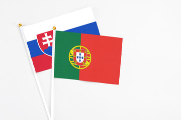 Portugal and Slovakia stick flags on white background. High quality fabric, miniature national flag. Peaceful global concept.White floor for copy space.