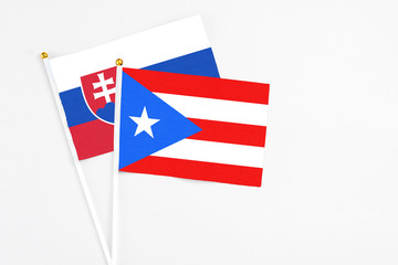 Puerto Rico and Slovakia stick flags on white background. High quality fabric, miniature national flag. Peaceful global concept.White floor for copy space.