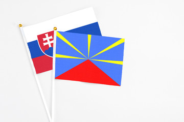 Reunion and Slovakia stick flags on white background. High quality fabric, miniature national flag. Peaceful global concept.White floor for copy space.