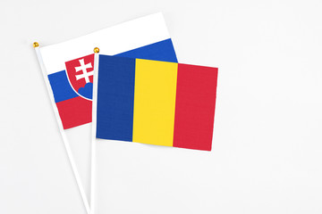 Romania and Slovakia stick flags on white background. High quality fabric, miniature national flag. Peaceful global concept.White floor for copy space.