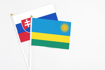 Rwanda and Slovakia stick flags on white background. High quality fabric, miniature national flag. Peaceful global concept.White floor for copy space.