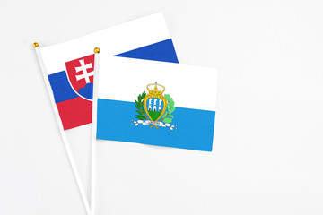 San Marino and Slovakia stick flags on white background. High quality fabric, miniature national flag. Peaceful global concept.White floor for copy space.