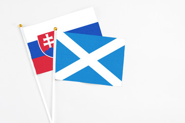 Scotland and Slovakia stick flags on white background. High quality fabric, miniature national flag. Peaceful global concept.White floor for copy space.