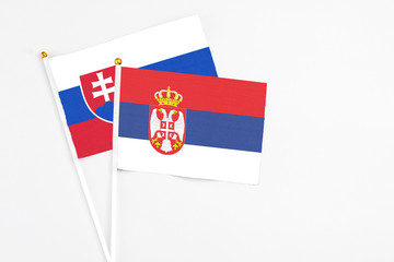Serbia and Slovakia stick flags on white background. High quality fabric, miniature national flag. Peaceful global concept.White floor for copy space.
