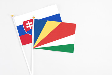 Seychelles and Slovakia stick flags on white background. High quality fabric, miniature national flag. Peaceful global concept.White floor for copy space.