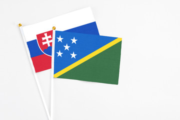 Solomon Islands and Slovakia stick flags on white background. High quality fabric, miniature national flag. Peaceful global concept.White floor for copy space.