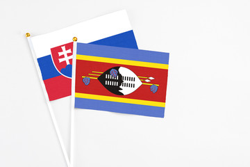 Fototapeta premium Swaziland and Slovakia stick flags on white background. High quality fabric, miniature national flag. Peaceful global concept.White floor for copy space.