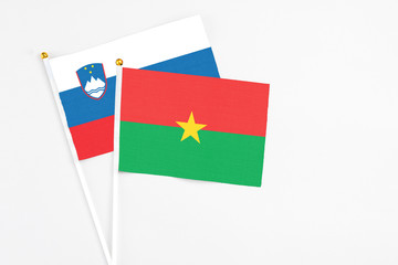 Burkina Faso and Slovenia stick flags on white background. High quality fabric, miniature national flag. Peaceful global concept.White floor for copy space.