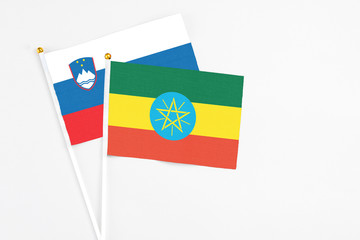 Ethiopia and Slovenia stick flags on white background. High quality fabric, miniature national flag. Peaceful global concept.White floor for copy space.