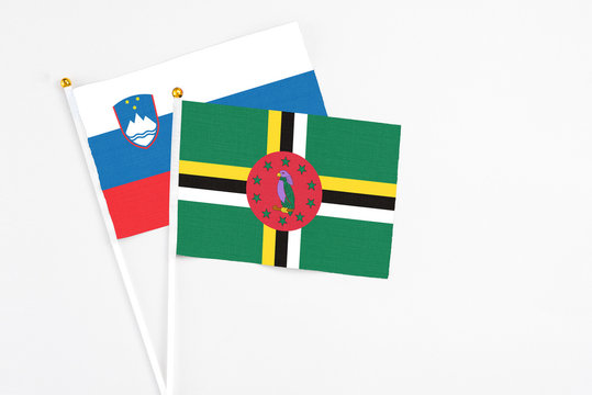 Dominica and Slovenia stick flags on white background. High quality fabric, miniature national flag. Peaceful global concept.White floor for copy space.