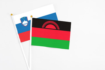 Malawi and Slovenia stick flags on white background. High quality fabric, miniature national flag. Peaceful global concept.White floor for copy space.