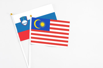 Malaysia and Slovenia stick flags on white background. High quality fabric, miniature national flag. Peaceful global concept.White floor for copy space.