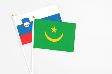 Mauritania and Slovenia stick flags on white background. High quality fabric, miniature national flag. Peaceful global concept.White floor for copy space.
