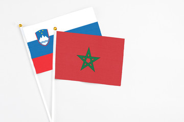 Morocco and Slovenia stick flags on white background. High quality fabric, miniature national flag. Peaceful global concept.White floor for copy space.