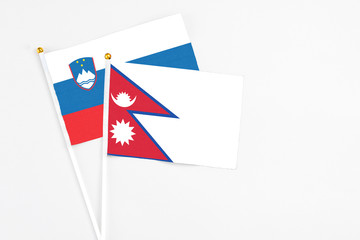 Nepal and Slovenia stick flags on white background. High quality fabric, miniature national flag. Peaceful global concept.White floor for copy space.