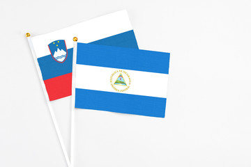Nicaragua and Slovenia stick flags on white background. High quality fabric, miniature national flag. Peaceful global concept.White floor for copy space.