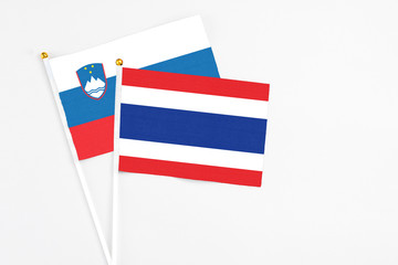 Thailand and Slovenia stick flags on white background. High quality fabric, miniature national flag. Peaceful global concept.White floor for copy space.