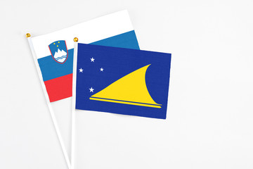 Tokelau and Slovenia stick flags on white background. High quality fabric, miniature national flag. Peaceful global concept.White floor for copy space.