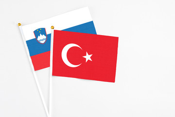 Turkey and Slovenia stick flags on white background. High quality fabric, miniature national flag. Peaceful global concept.White floor for copy space.