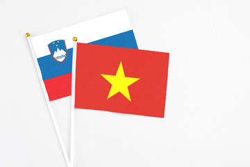 Vietnam and Slovenia stick flags on white background. High quality fabric, miniature national flag. Peaceful global concept.White floor for copy space.