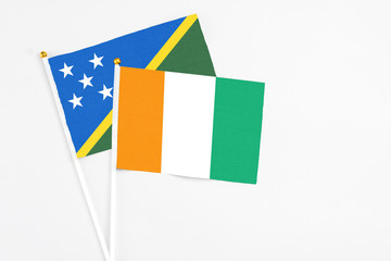 Cote D'Ivoire and Solomon Islands stick flags on white background. High quality fabric, miniature national flag. Peaceful global concept.White floor for copy space.