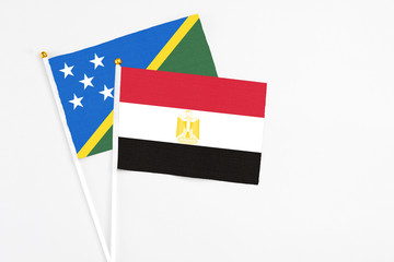 Egypt and Solomon Islands stick flags on white background. High quality fabric, miniature national flag. Peaceful global concept.White floor for copy space.