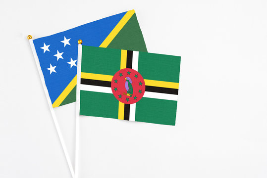 Dominica and Solomon Islands stick flags on white background. High quality fabric, miniature national flag. Peaceful global concept.White floor for copy space.