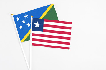 Liberia and Solomon Islands stick flags on white background. High quality fabric, miniature national flag. Peaceful global concept.White floor for copy space.