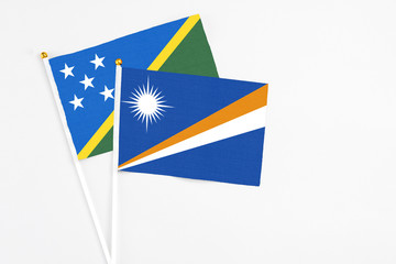 Marshall Islands and Solomon Islands stick flags on white background. High quality fabric, miniature national flag. Peaceful global concept.White floor for copy space.