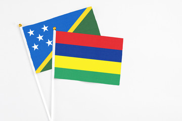 Mauritius and Solomon Islands stick flags on white background. High quality fabric, miniature national flag. Peaceful global concept.White floor for copy space.