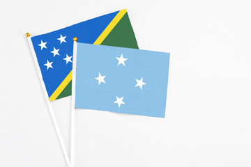 Micronesia and Solomon Islands stick flags on white background. High quality fabric, miniature national flag. Peaceful global concept.White floor for copy space.
