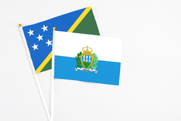 San Marino and Solomon Islands stick flags on white background. High quality fabric, miniature national flag. Peaceful global concept.White floor for copy space.