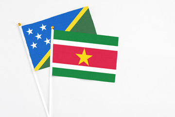 Suriname and Solomon Islands stick flags on white background. High quality fabric, miniature national flag. Peaceful global concept.White floor for copy space.